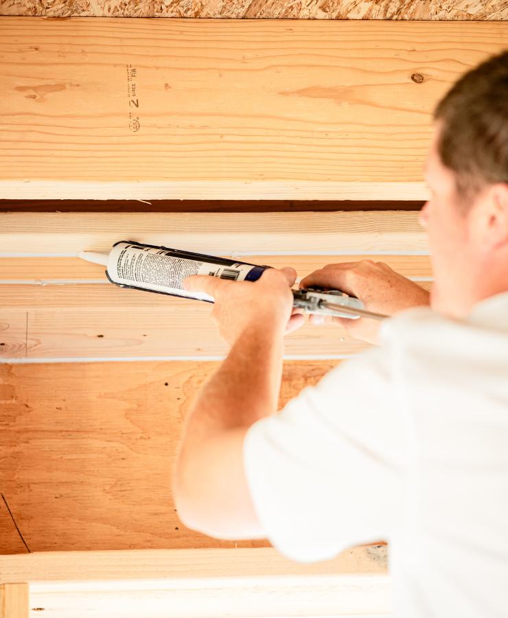 Man sealing gaps on ceiling